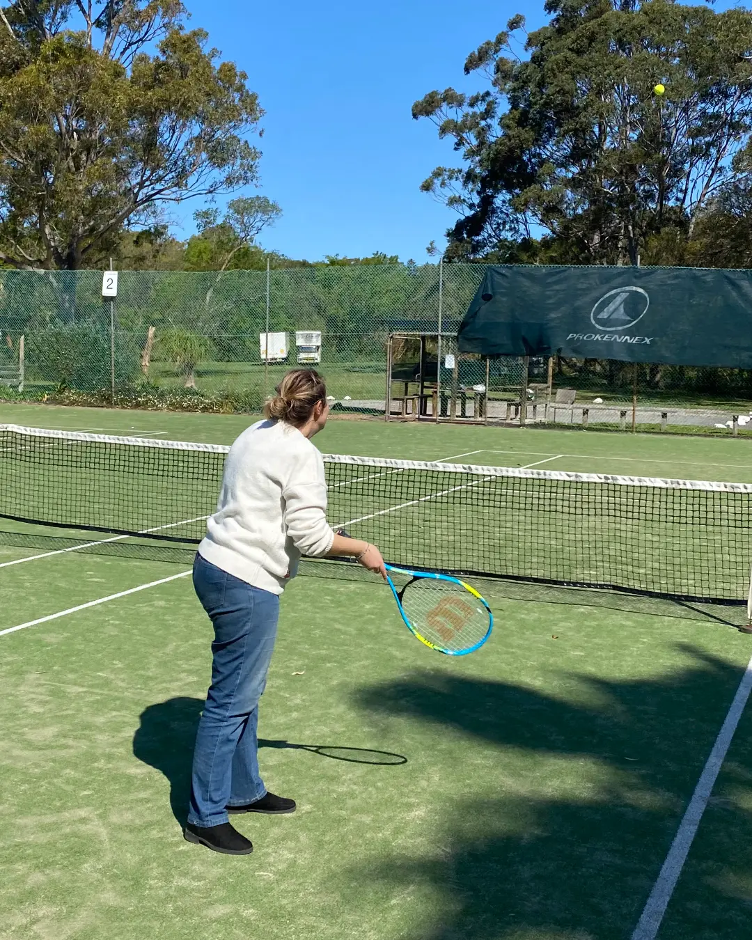 A participant playing tennis on an outdoor court on a sunny day